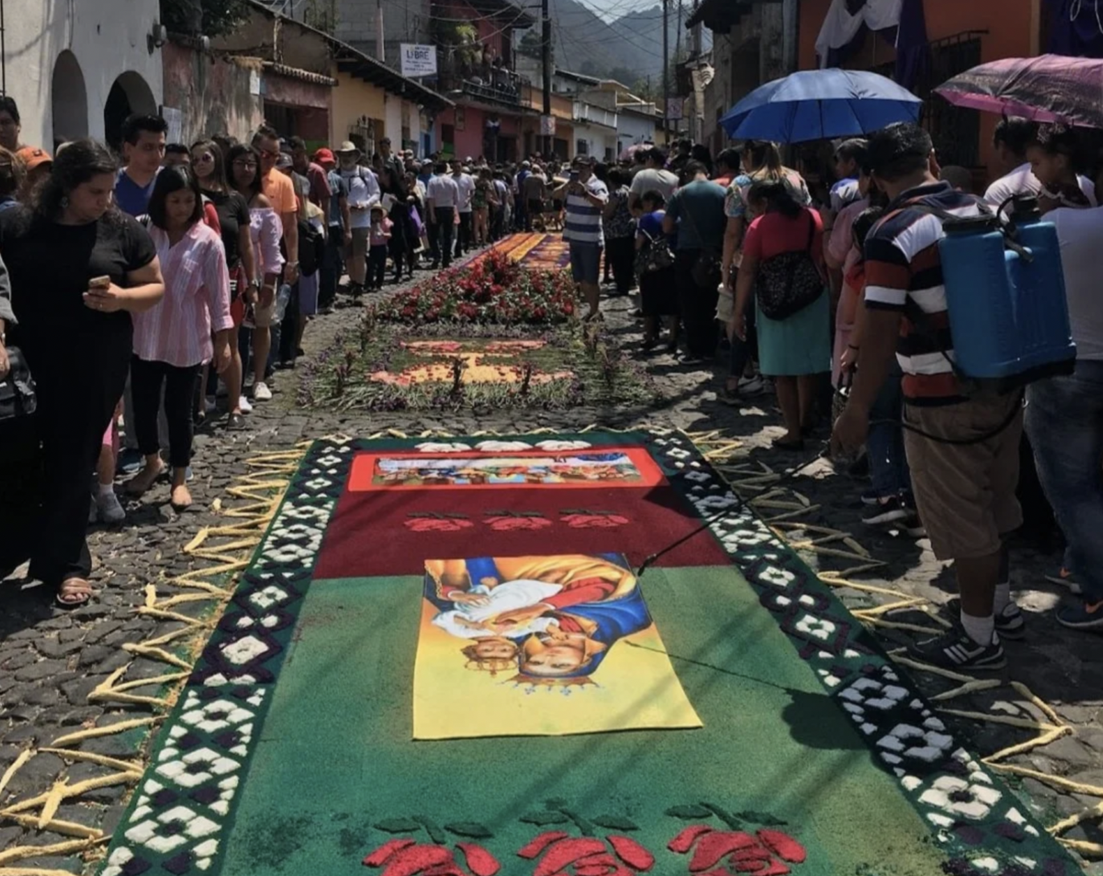 During a procession people are admiring the alfombras in Guatemala displaying an image of baby Jesus and the virgin Mary