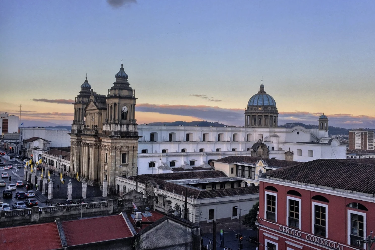 Guatemala City at susnset with a large church, a white building, and red buildings