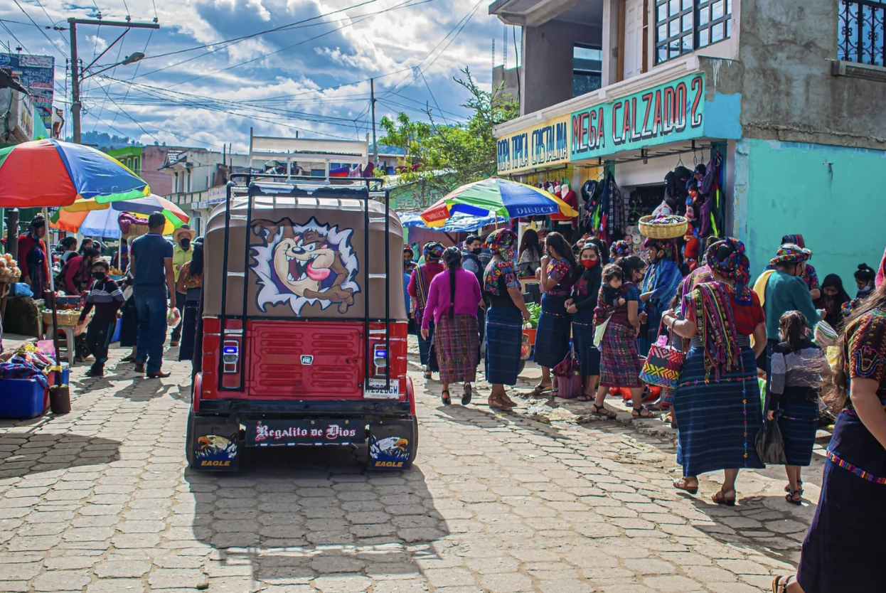 A tuk-tuk is driving through a busy street in Lake Atitlan, Guatemala