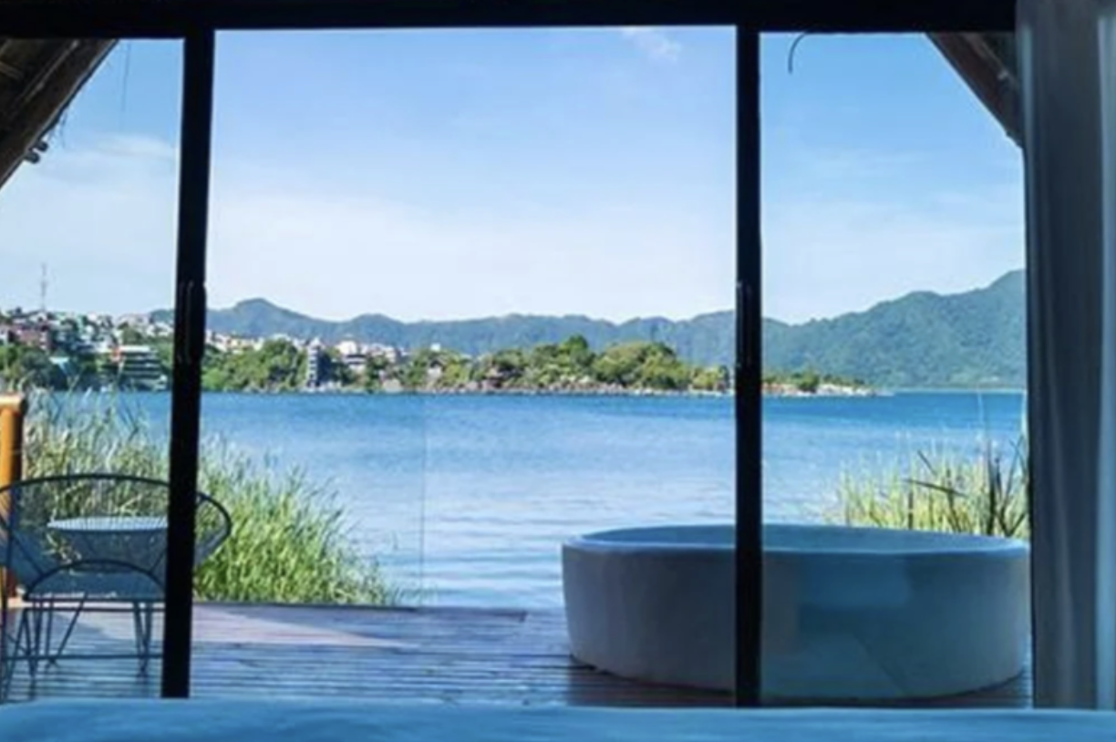 A hotel tub is on a wooden deck overlooking Lake Atitlan at a hotel 