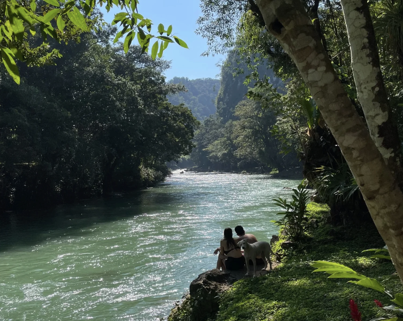 A couple is sitting on the riverbanks in the forest of Semuc Champey