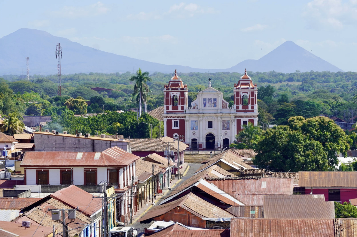 The city view of Granada, Nicaragua with a red church and the volcanoes and mountains in the background