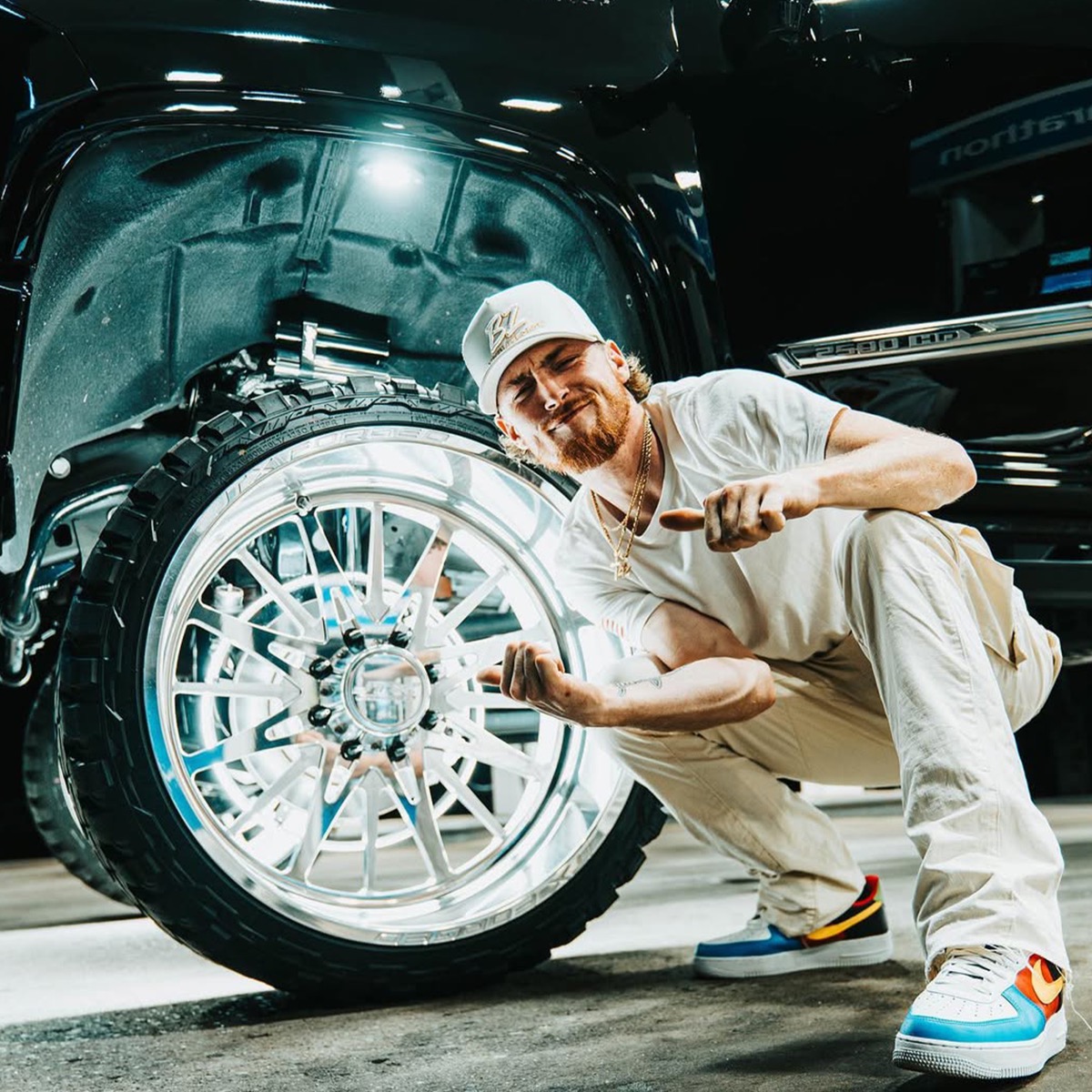 Bailey Zimmerman crouching next to a lifted truck wheel