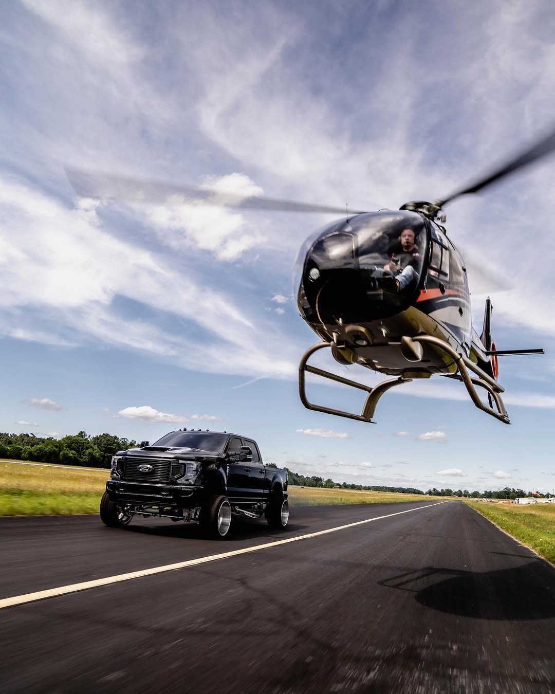 Helicopter and lifted F-250 racing down a runway