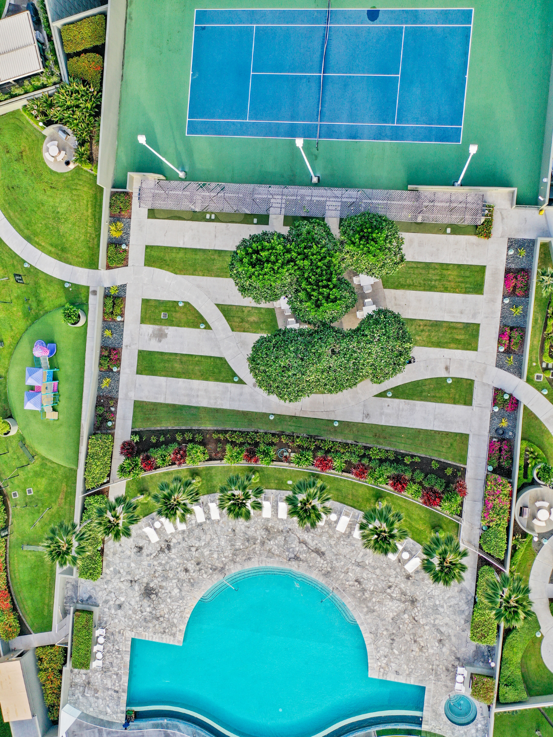 Vista aérea de las amenidades de una comunidad: piscina, cancha de tenis y áreas verdes