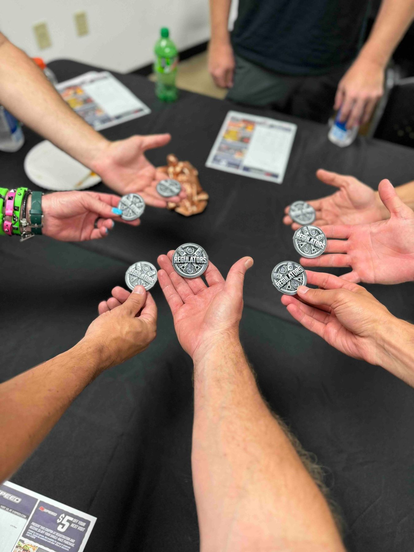 Regulators Car Club members holding up challenge coins