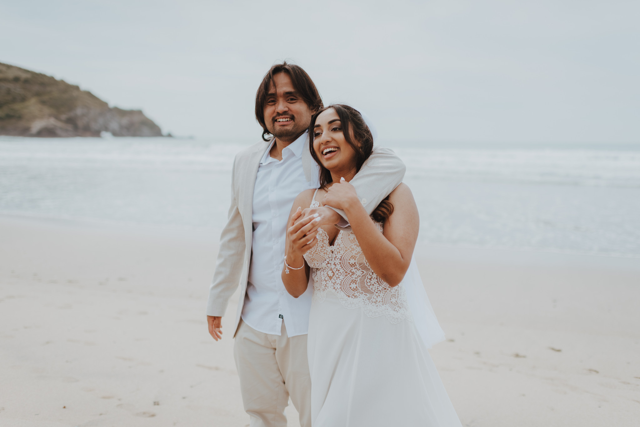 newlyweds on beach laughing at guests to their elopement newlyweds on beach laughing at guests to their elopement