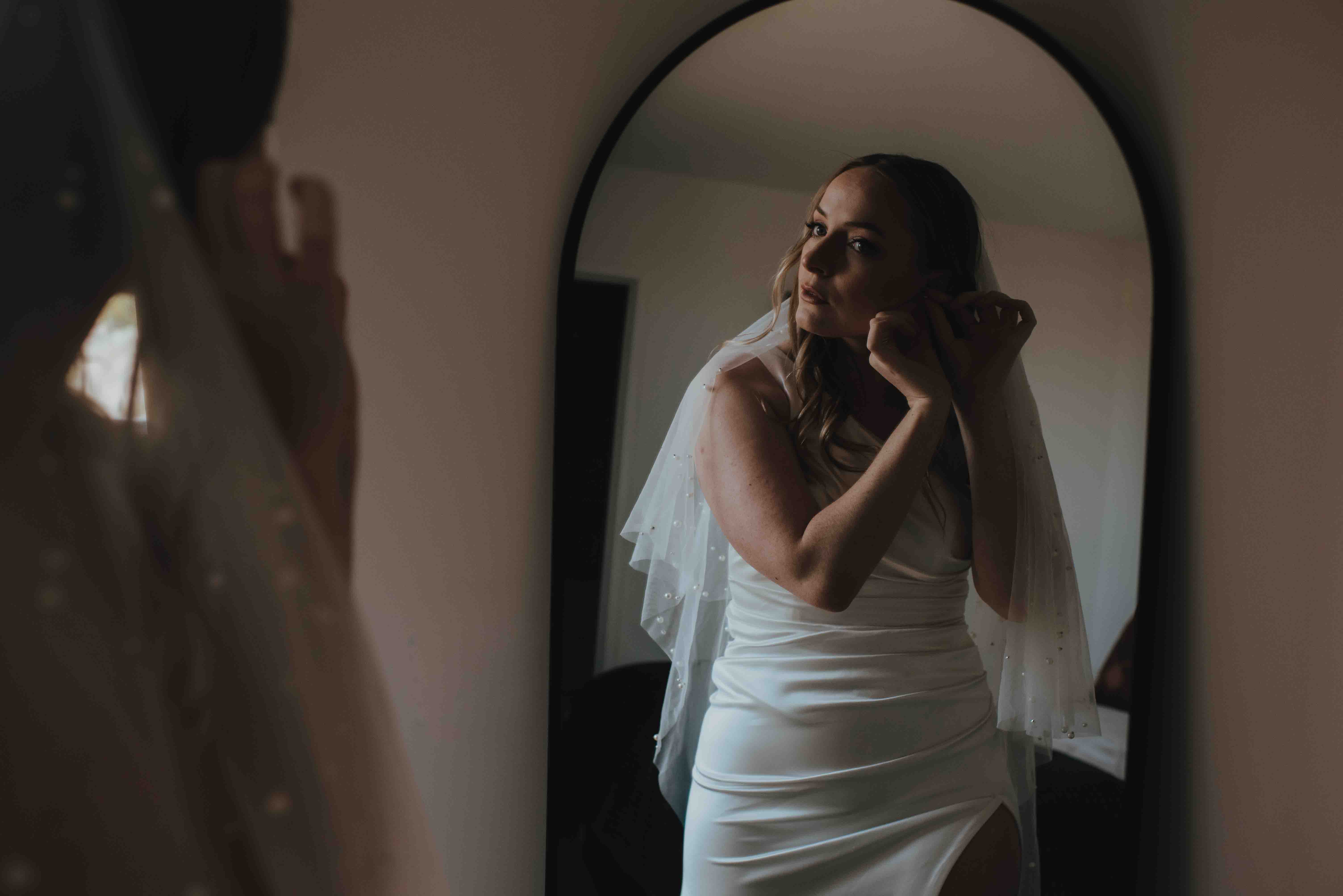 bride checking her earrings in the mirror