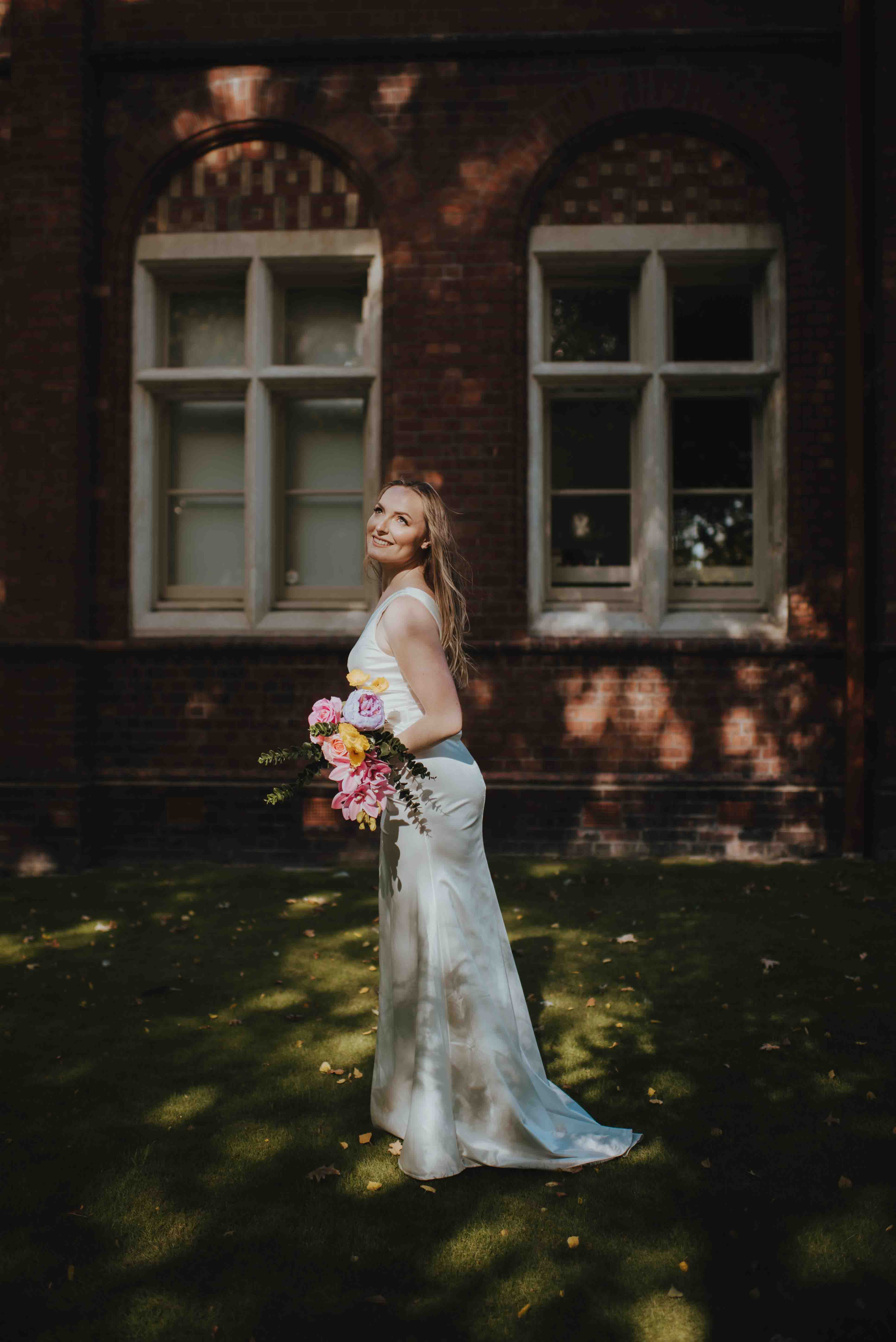 bride standing outside brick heritage building