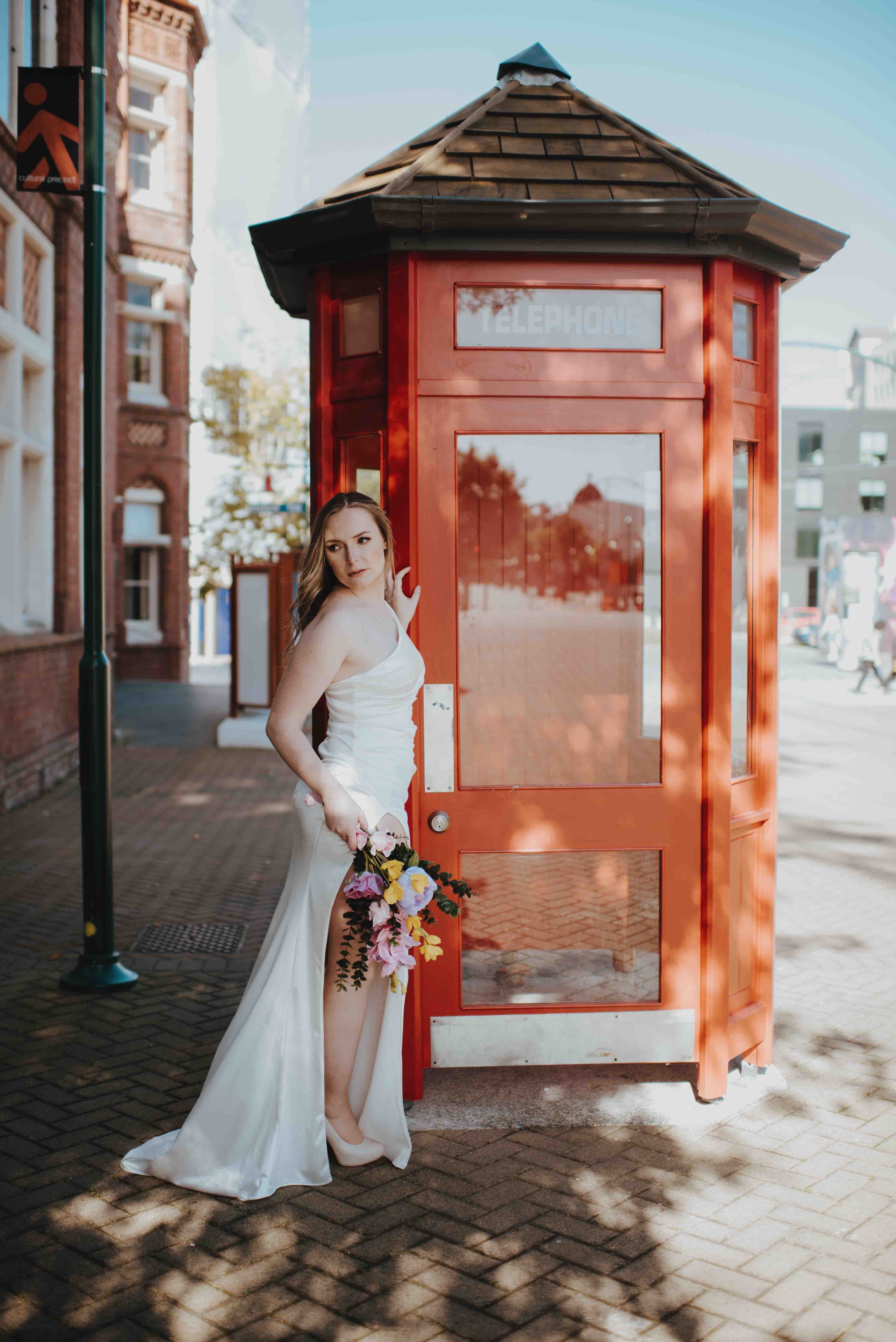 bride leaning against telephone box