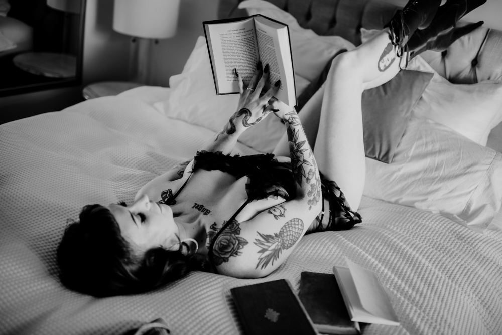 person lying on bed reading book in a bodysuit
