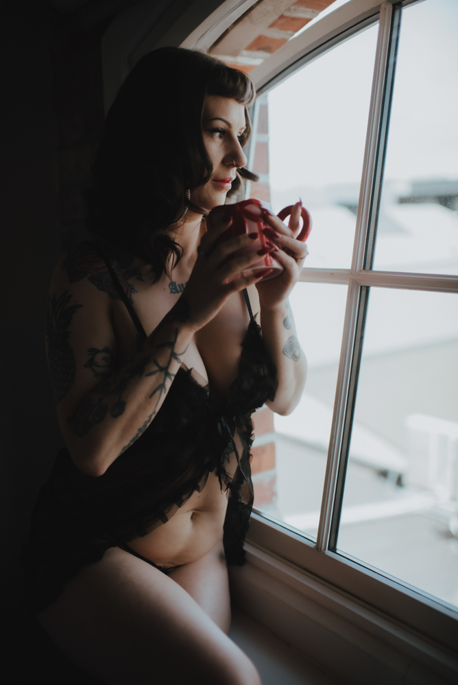 standing with cup of coffee looking out of window standing with cup of coffee looking out of window