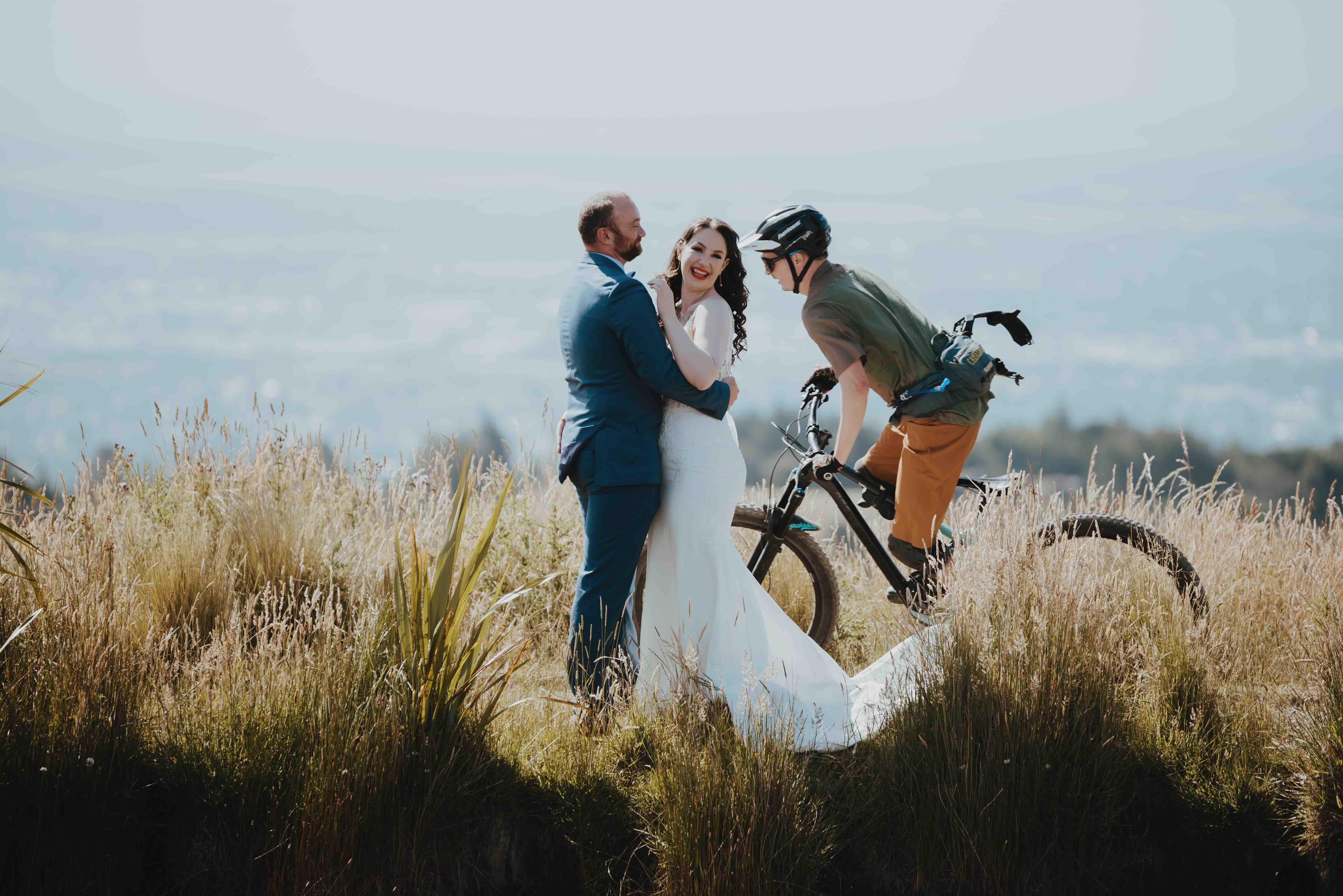 cyclist riding behind couple for their wedding photos cyclist riding behind couple for their wedding photos