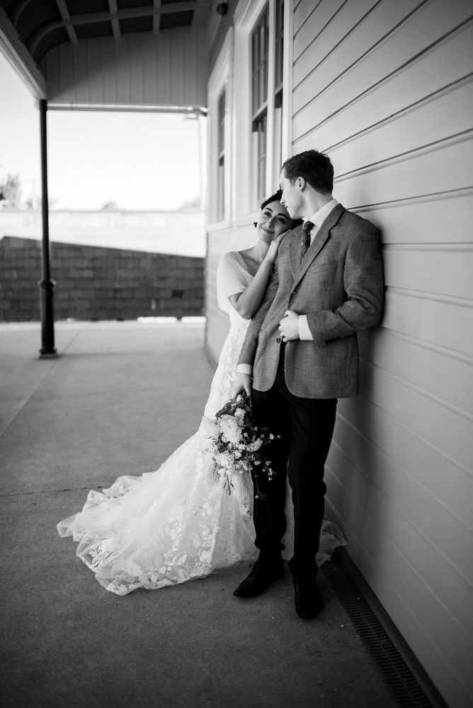 couple smiling leaning against eachother and a wall couple smiling leaning against eachother and a wall