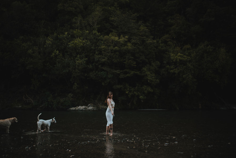 woman standing in a low river surrounded by deep green new zealand bush woman standing in a low river surrounded by deep green new zealand bush
