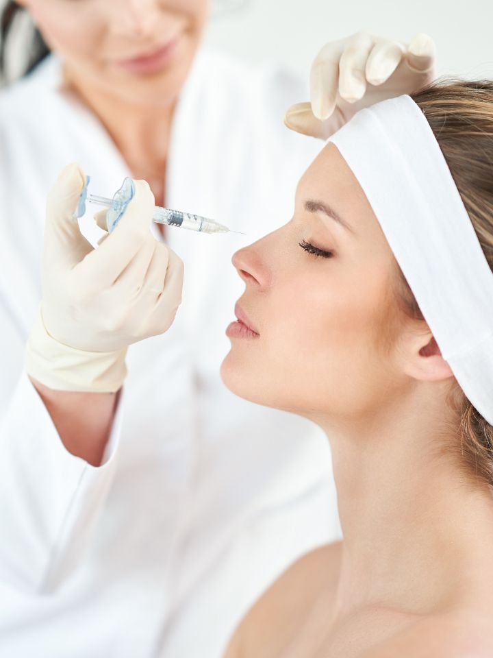 A professional administering Botox injections to a person's forehead, with the individual