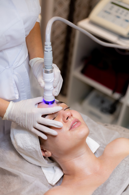 A woman receiving a laser skin resurfacing treatment at a med spa in Temecula, with the technician using a laser device on her face.