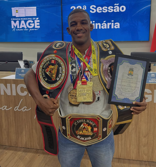 Fernando Gorila recebendo moção de homenagem na Câmara Municipal de Magé, com três cinturões de jiu-jitsu e medalhas