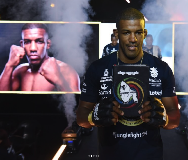 Fernando Gorila entrando no Jungle Fight 154 com a Bíblia nas mãos, sob a fumaça da entrada