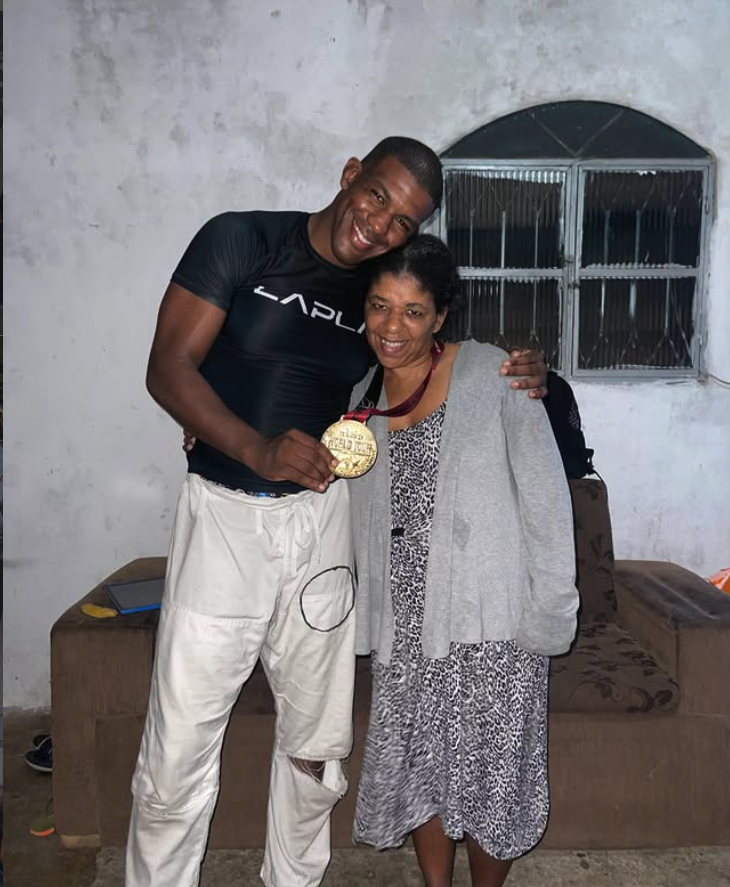 Fernando Gorila em casa com a mãe, de kimono, ela segurando a medalha de ouro dele