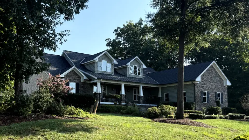 New dark architectural shingle roof on a craftsman home with gabled dormers and a stone front porch