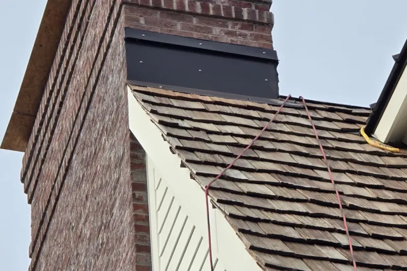 Hand-laid cedar shake roof with metal flashing where it meets a brick chimney