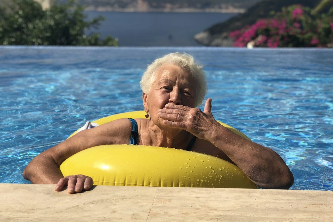 Smiling woman on a yellow pool float blowing a kiss