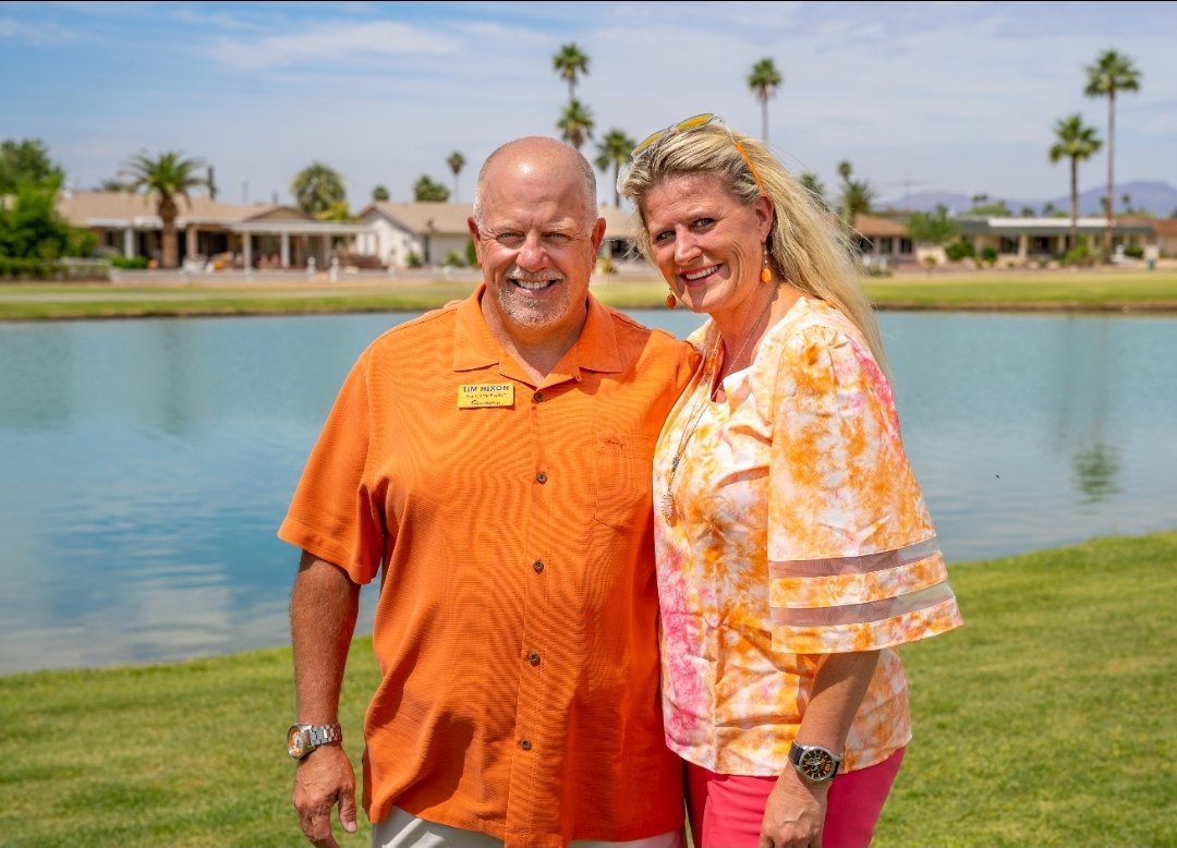 Amy and Tim Nixon in orange by a lake in Sun City, Arizona