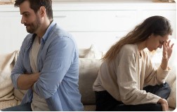 Couple sitting apart on a couch, distant and disconnected