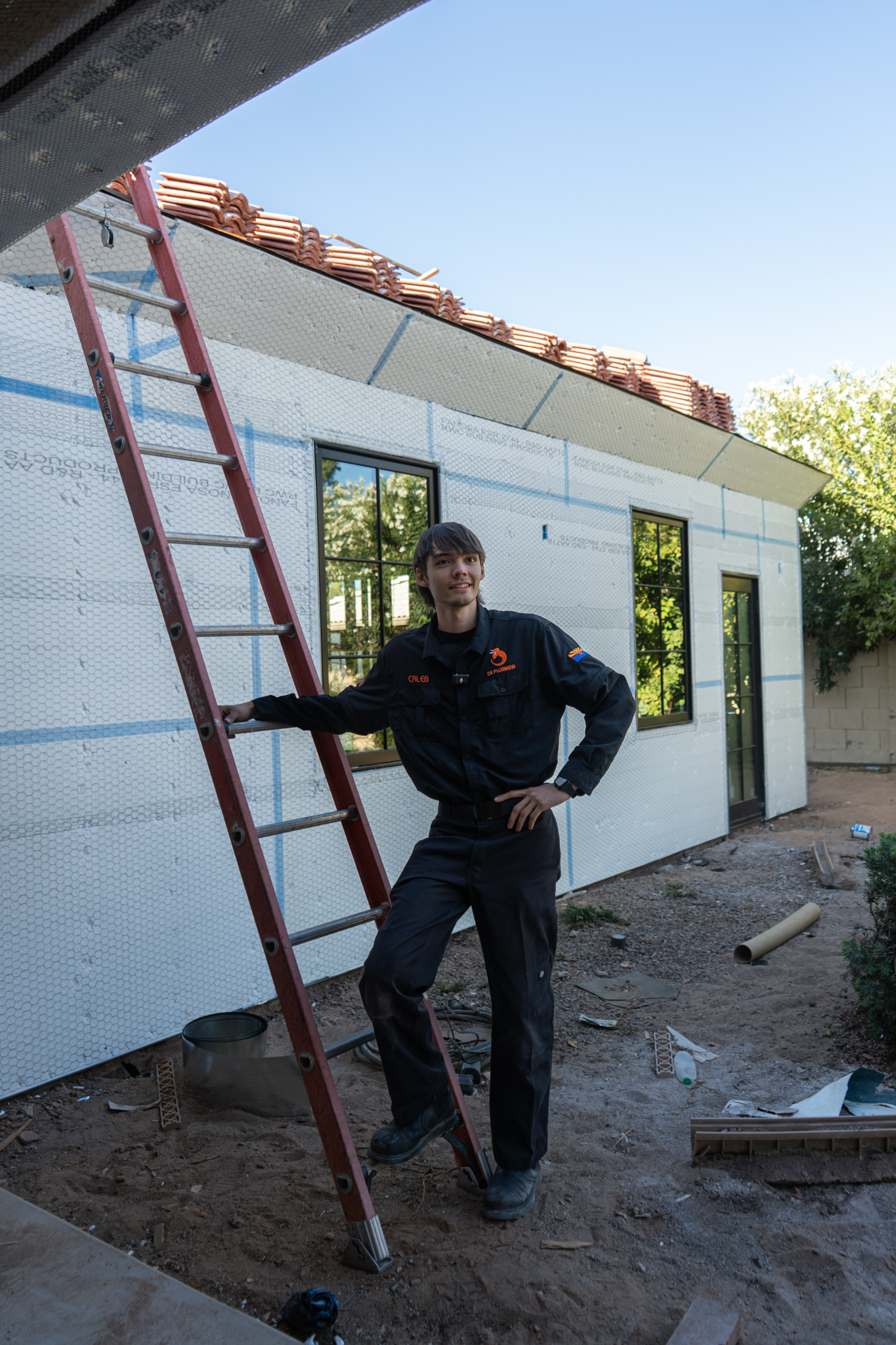 Caleb, OX Plumbing worker, in full uniform at a new build