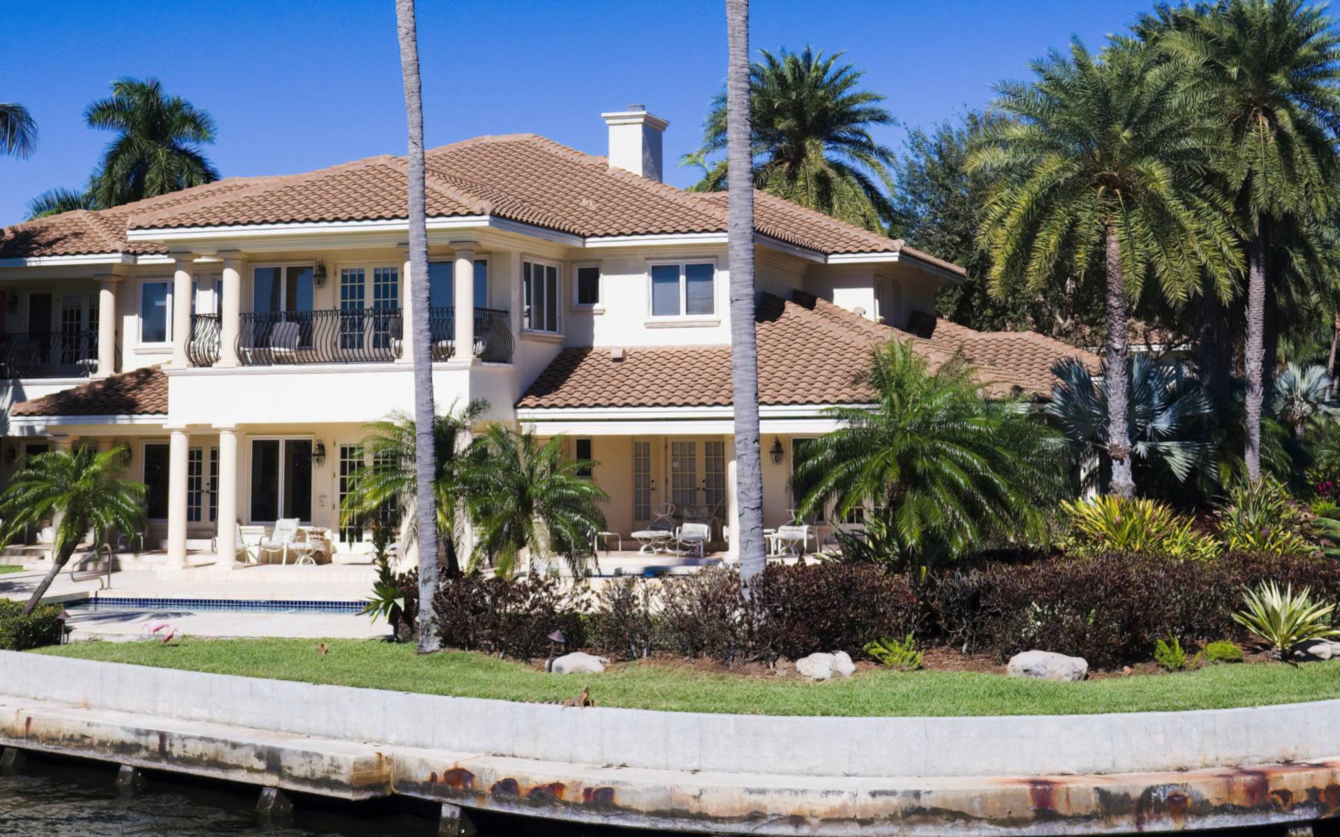 Waterfront home with palm trees along a seawall