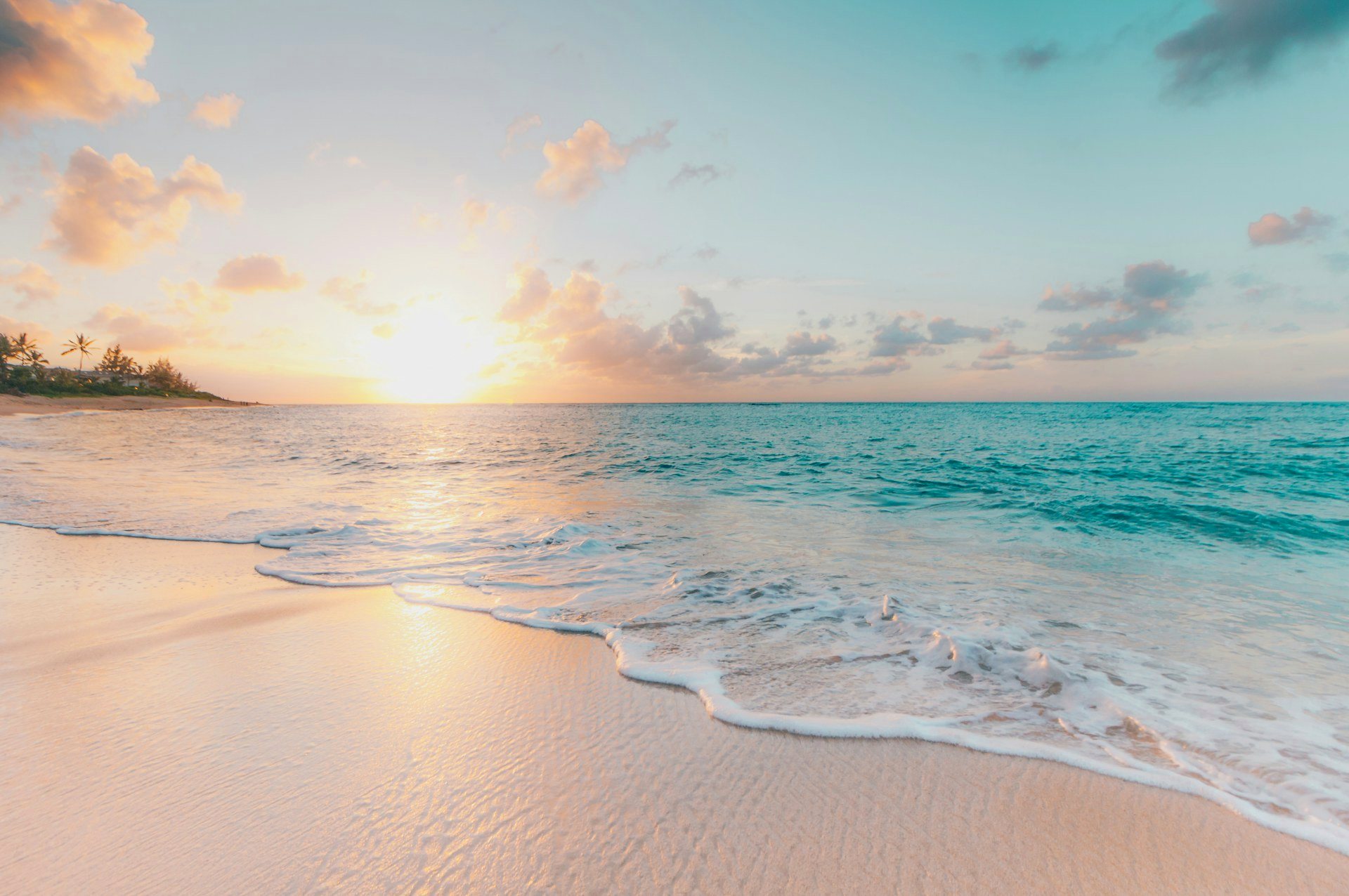 Turquoise ocean surf on a sandy beach at sunrise
