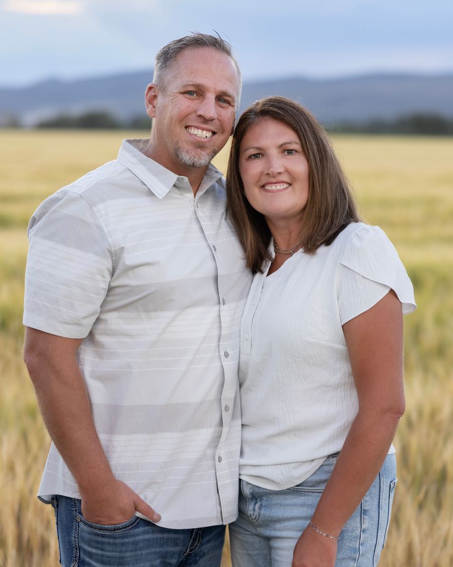 Brady and Heidi Breinholt standing together in a golden wheat field at dusk