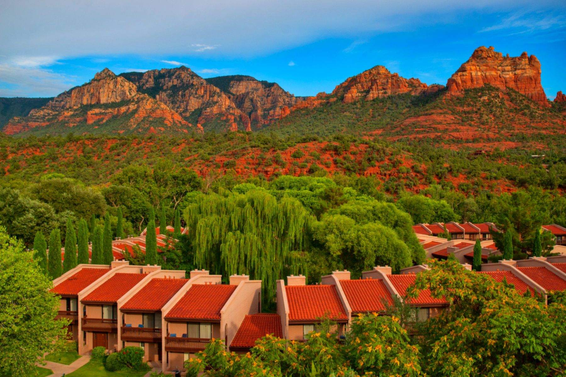 Residential community beneath red rock cliffs in desert light
