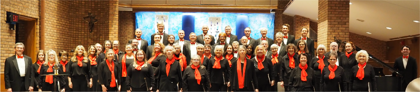 The singers of Chorus Polaris in black with red scarves, standing together in a sanctuary