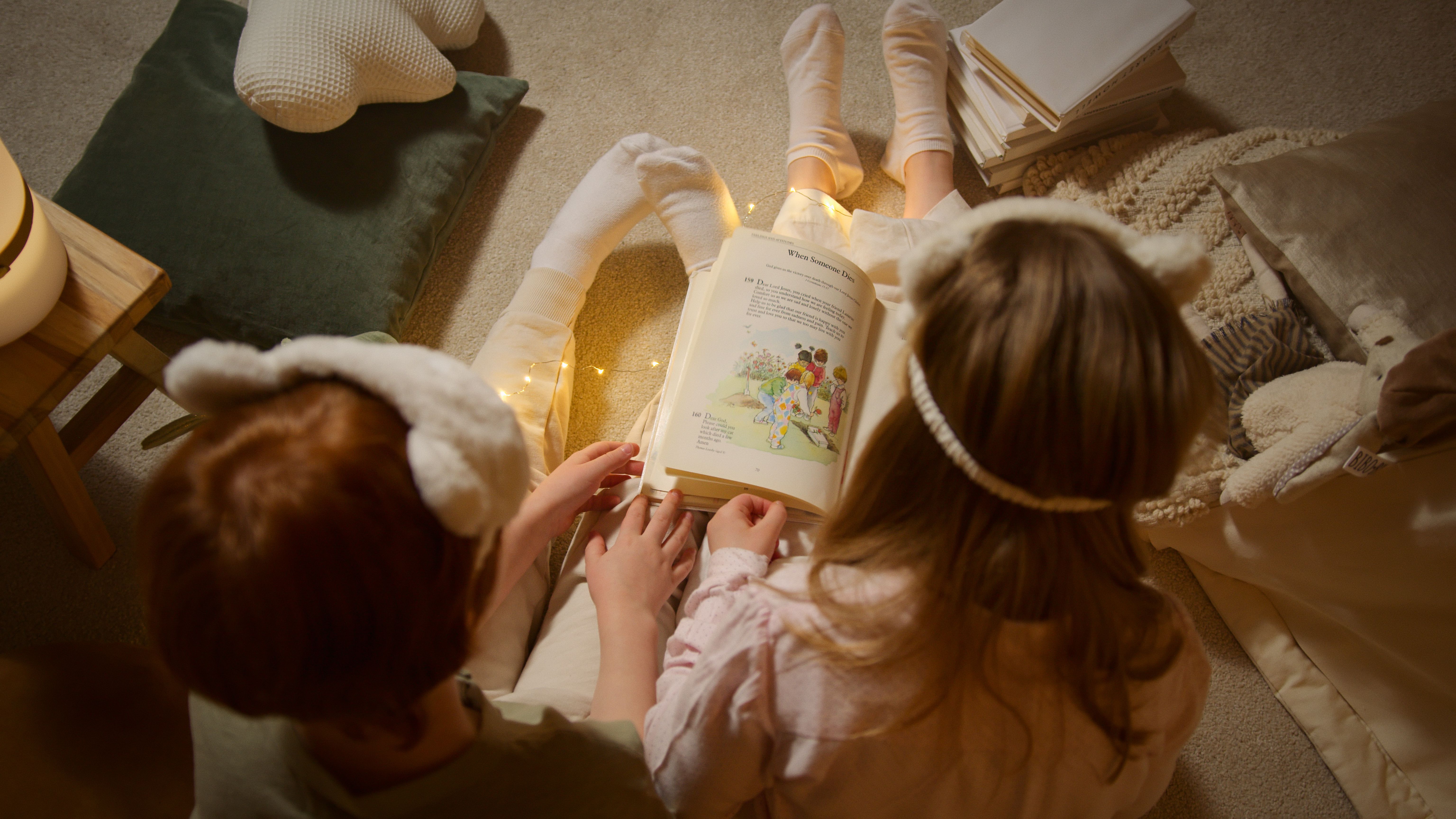 two children read a storybook, pictured from above with no faces included two children read a storybook, pictured from above with no faces included