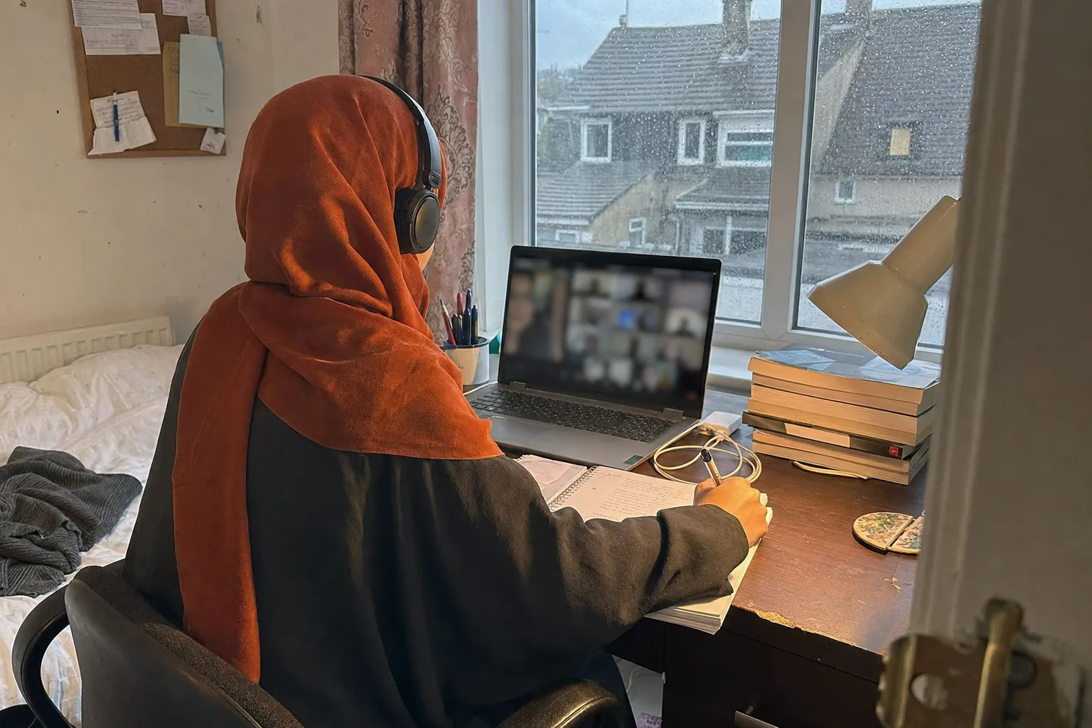 Muslim primary school student smiling while engaging in a live online British curriculum lesson