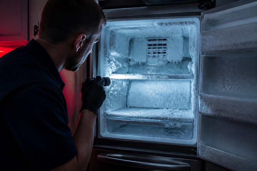 Technician inspecting heavy frost buildup inside an open freezer