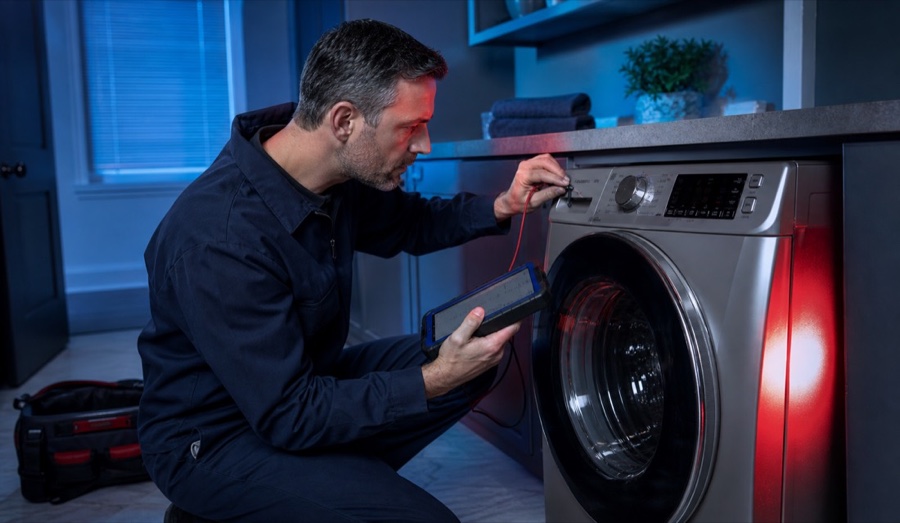 Technician checking washer controls with a diagnostic tool