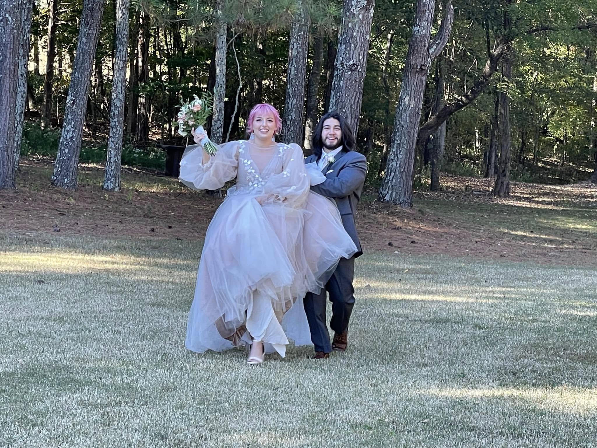 Newlyweds laughing and walking across a sunny lawn