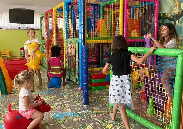 Bambini nel playground coperto con scivoli e strutture colorate