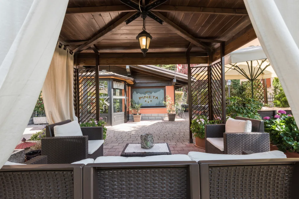 Il gazebo in legno davanti all'hotel, con le tende bianche e i divanetti