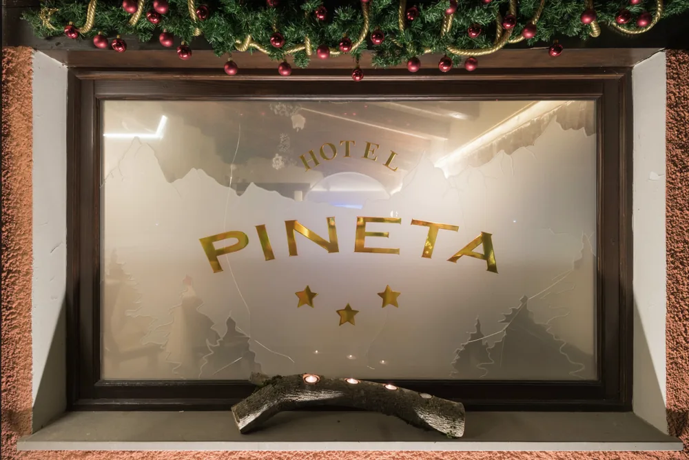 L'insegna dell'Hotel Pineta incisa nel vetro, con il festone di Natale
