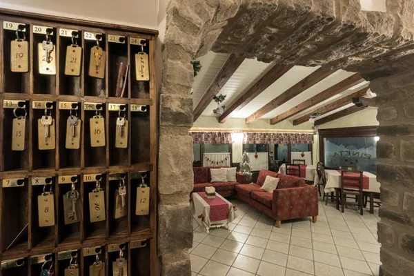 Il portachiavi in legno della reception e, oltre l'arco in pietra, il salotto con i tavoli apparecchiati