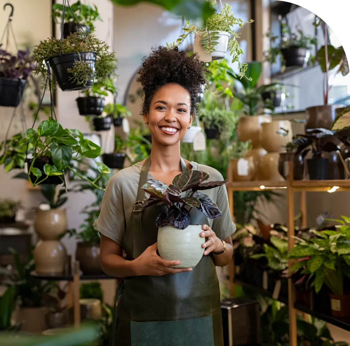 Small business owner smiling while holding a potted plant, representing confident entrepreneurs supported by Promise Bookkeeping.