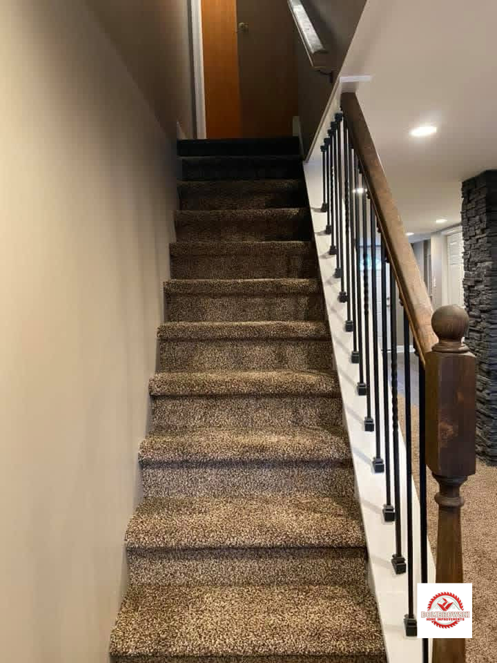 Carpeted staircase with iron balusters and wood handrail