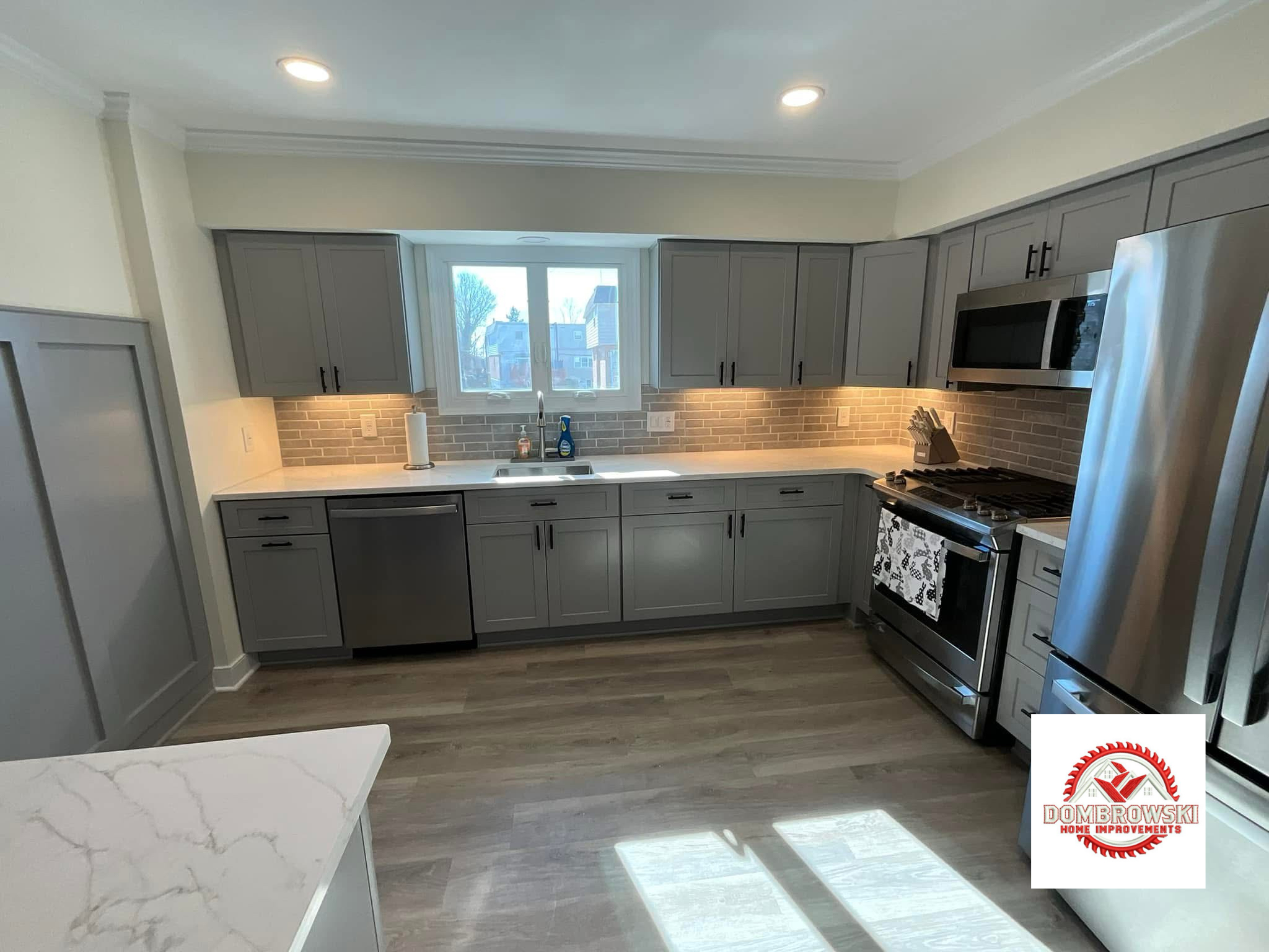 Gray shaker cabinets with brick backsplash and quartz island, Dombrowski kitchen remodeling Bucks County PA