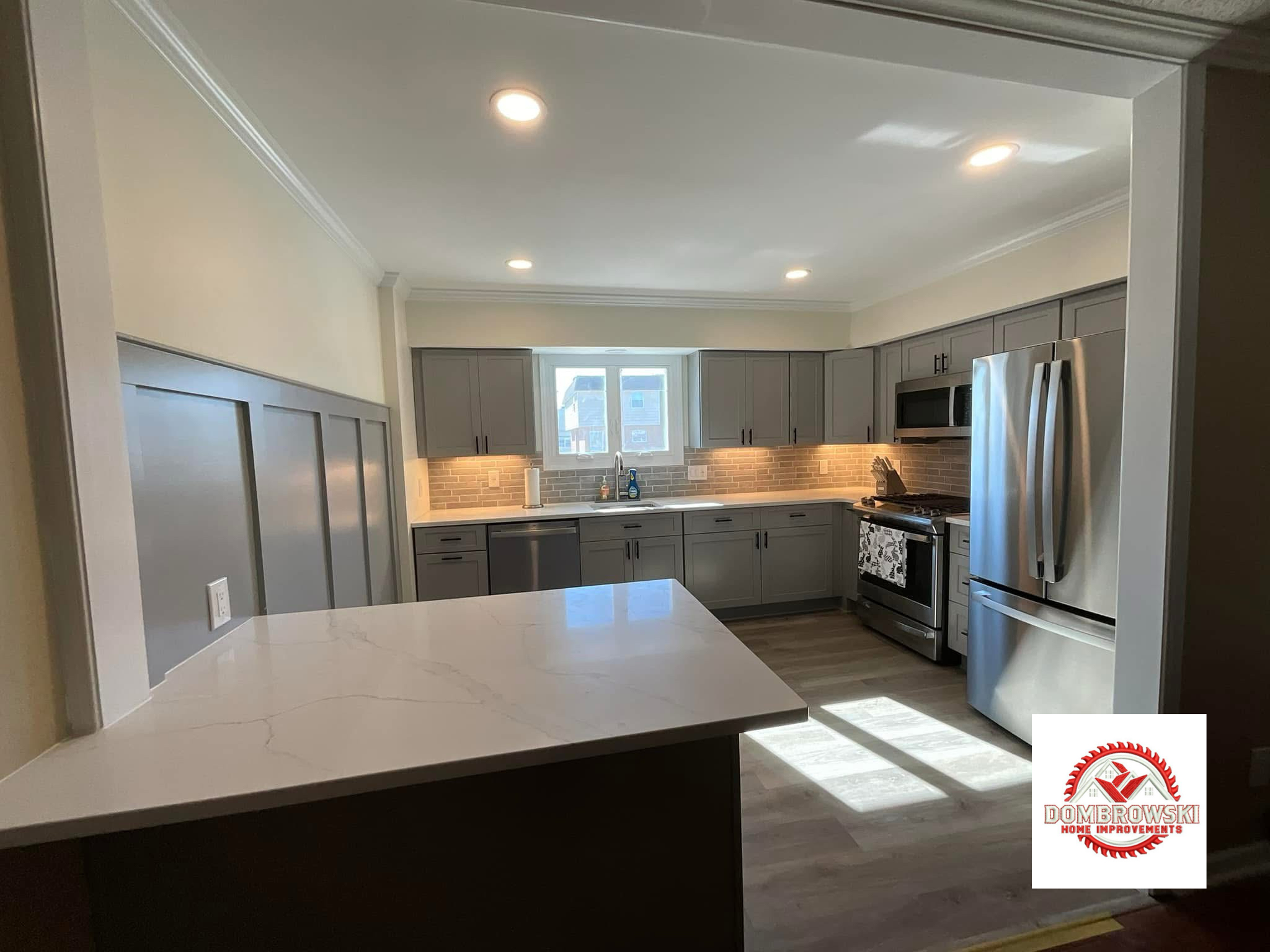Full kitchen view: gray shaker cabinets, brick backsplash, stainless appliances