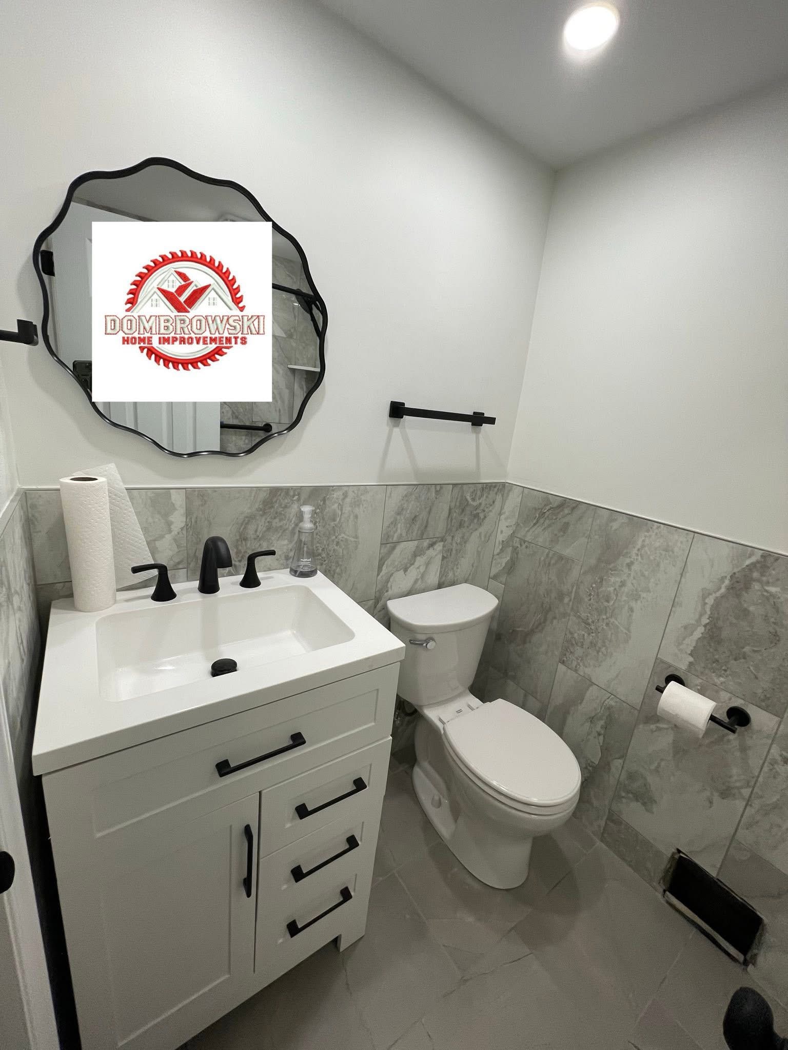 Dark vanity with quartz top, black hardware and gray tile floor