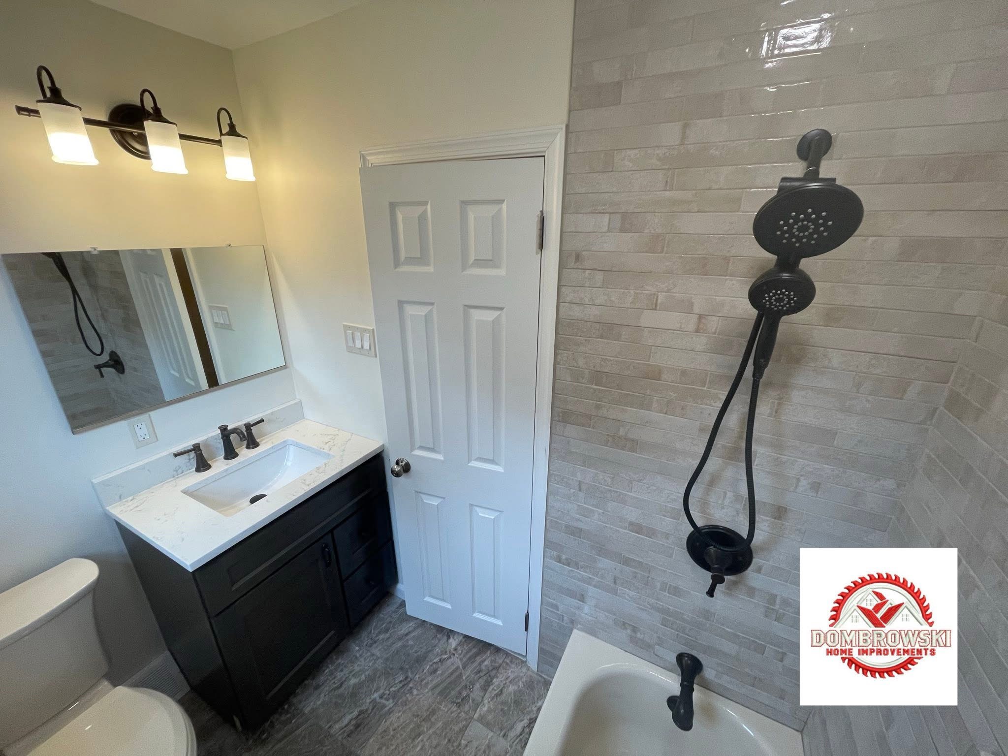 Dark vanity with quartz top, black hardware and brick tile shower